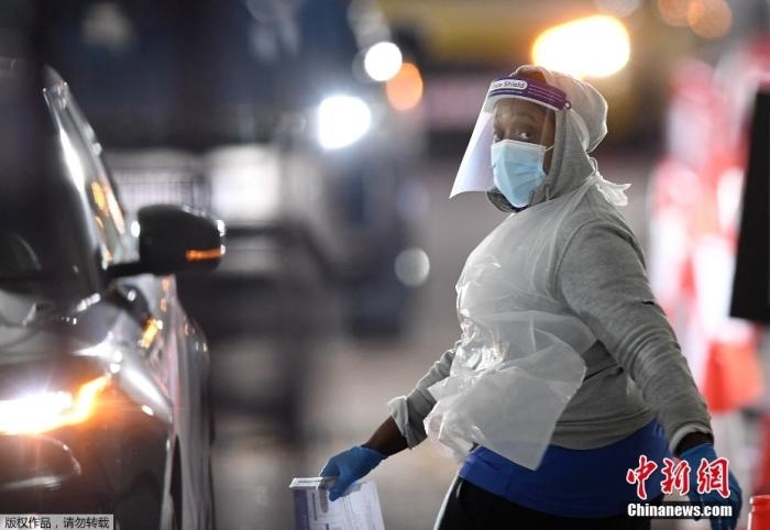 當(dāng)?shù)貢r(shí)間12月18日，英國政府公布的數(shù)據(jù)顯示，當(dāng)天英國新增奧密克戎毒株感染病例10059例。鑒于奧密克戎毒株感染病例激增，住院人數(shù)不斷上升，倫敦市長宣布倫敦進(jìn)入“重大事故”狀態(tài)。圖為倫敦的一個(gè)免下車檢測中心，一名醫(yī)務(wù)工作者正準(zhǔn)備對(duì)司機(jī)進(jìn)行核酸檢測。