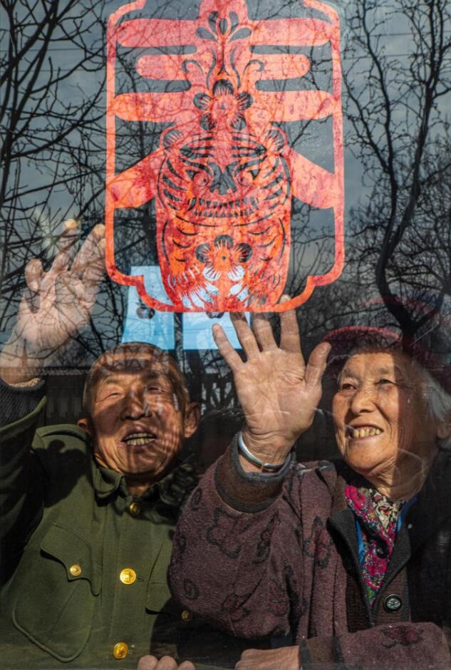 臘月里，霍州市師莊鄉(xiāng)馮南垣村村民師榮光(左)在災(zāi)后重建的新家里貼窗花。(霍州市委宣傳部供圖)