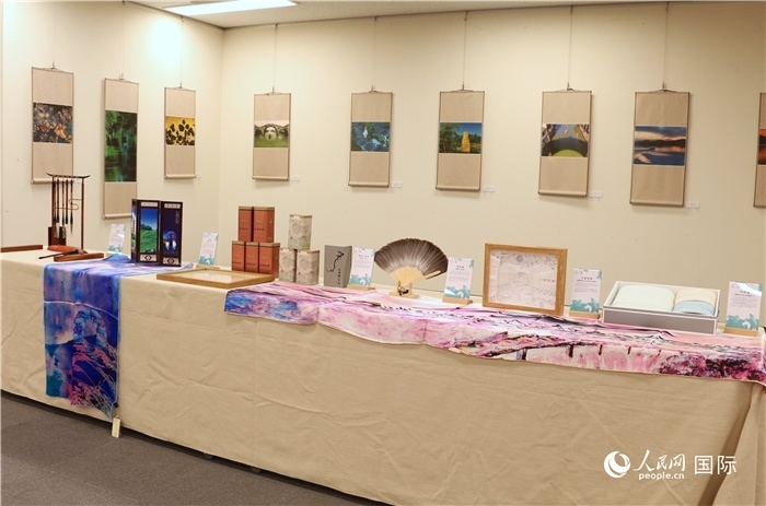 現(xiàn)場展出的馮學(xué)敏攝影作品與湖州市特色工藝品。（人民網(wǎng) 許可攝）