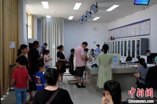 圖為在戶籍辦證廳內(nèi)排隊(duì)等待的家長和孩子。劉俊聰 攝