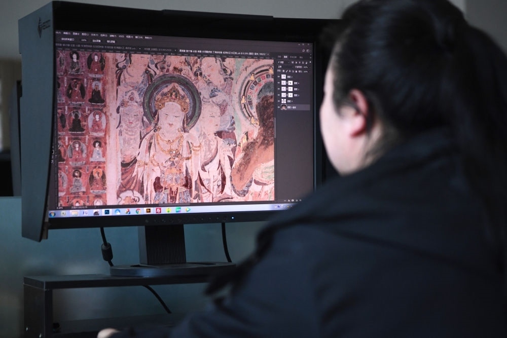 敦煌研究院文物數(shù)字化保護(hù)團(tuán)隊(duì)圖像處理人員年海麗在拼接壁畫圖像（2023年4月25日攝）。數(shù)字化探索為莫高窟的保護(hù)與傳承開辟了全新路徑，數(shù)字技術(shù)讓敦煌文物走出洞窟，跨出國門，走向“永久保存、永續(xù)利用”。新華社記者 陳斌 攝