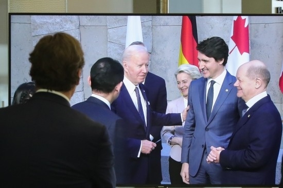 2022年3月24日，在比利時布魯塞爾的北約總部，一名男子觀看屏幕上美國總統(tǒng)拜登（右四）、歐盟委員會主席馮德萊恩（右三）、加拿大總理特魯多（右二）、德國總理朔爾茨（右一）出席七國集團峰會合影儀式的畫面。新華社記者鄭煥松攝