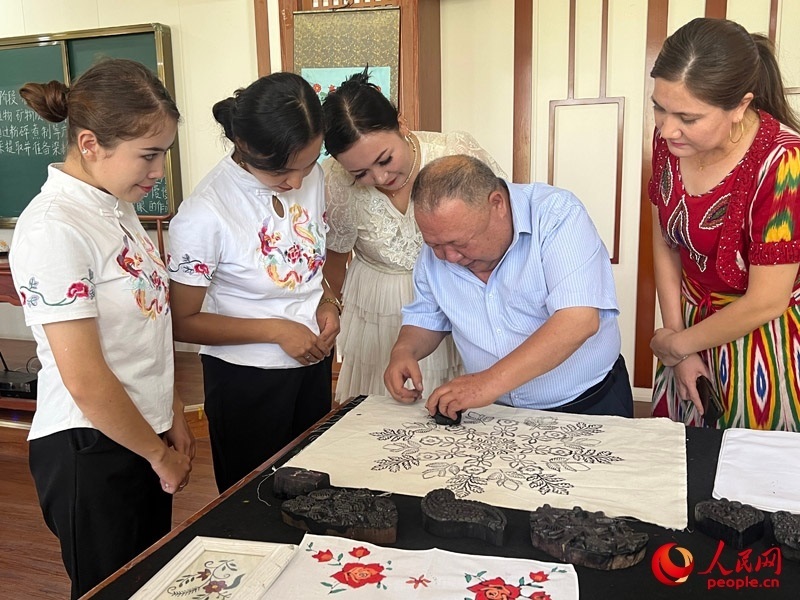 國(guó)家級(jí)非物質(zhì)文化遺產(chǎn)模戳印花布技藝傳承人吾吉阿西木?吾舒爾展示模戳印花布的制作過程。人民網(wǎng)記者 常雪梅攝