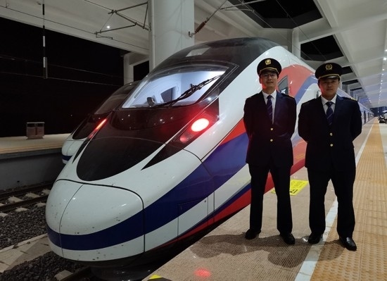 劉銀能（右一）與中國師父鄔俊鴻在動車組前合影。受訪者供圖