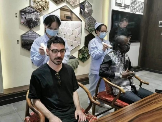 2023“一帶一路”媒體合作論壇聯(lián)合采訪團團員在九牛草展示館體驗艾灸。（本報記者 黃超攝）