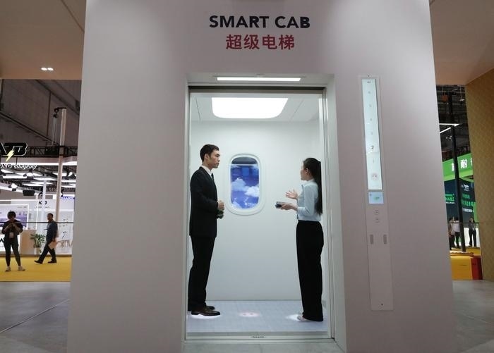 11月5日，工作人員（右）在第六屆進博會上向參觀者介紹奧的斯公司全新推出的超級電梯。