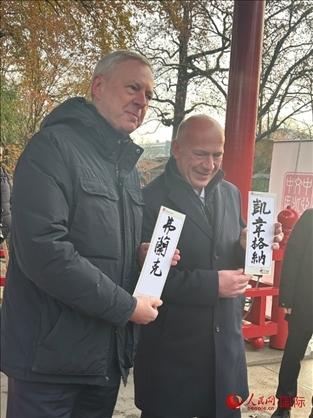 柏林市長韋格納（右）、動物園監(jiān)事會主席布魯克曼（左）手持中國文化中心工作人員現(xiàn)場手書的中文名字。人民網(wǎng)記者 徐馨攝