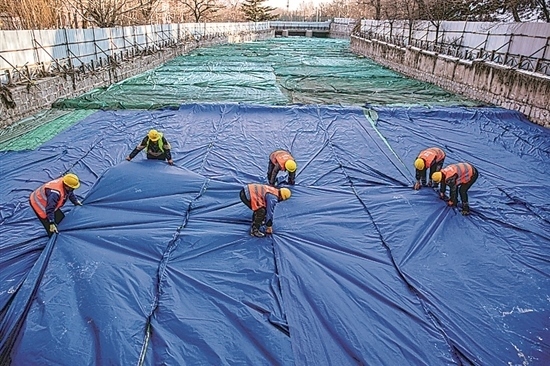 1月3日，房山區(qū)東風街道，工人正在修復的河道內給混凝土鋪設保溫布。