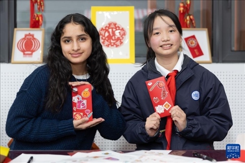 1月28日，美國馬斯卡廷中學(xué)學(xué)生（左）和復(fù)旦大學(xué)第二附屬學(xué)校學(xué)生展示互相送出的寫有寄語祝福的紅包。 新華社記者 王翔 攝