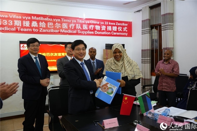 江蘇省蘇北人民醫(yī)院黨委書記束余聲與桑衛(wèi)生部首席秘書哈比巴交換捐贈書。中國援桑醫(yī)療隊供圖