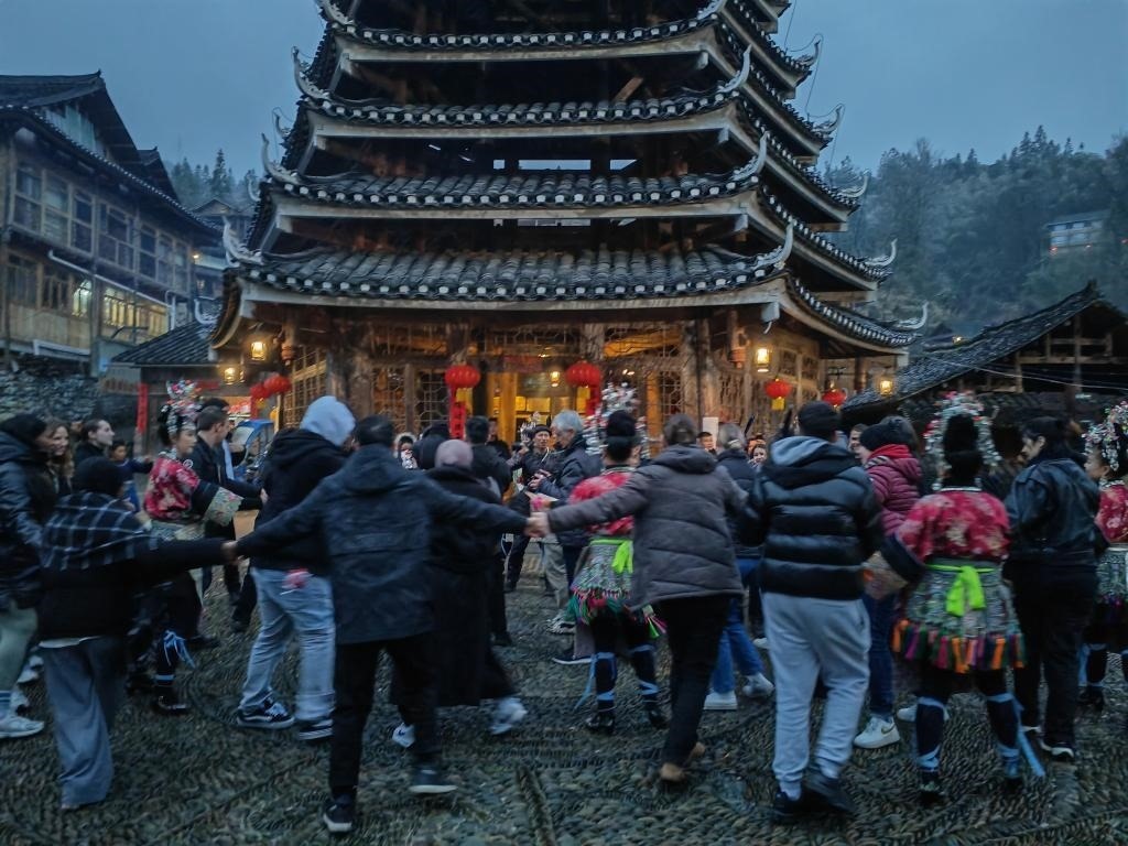 法國青年與當?shù)卮迕駹渴痔?。新華社記者 羅羽 攝