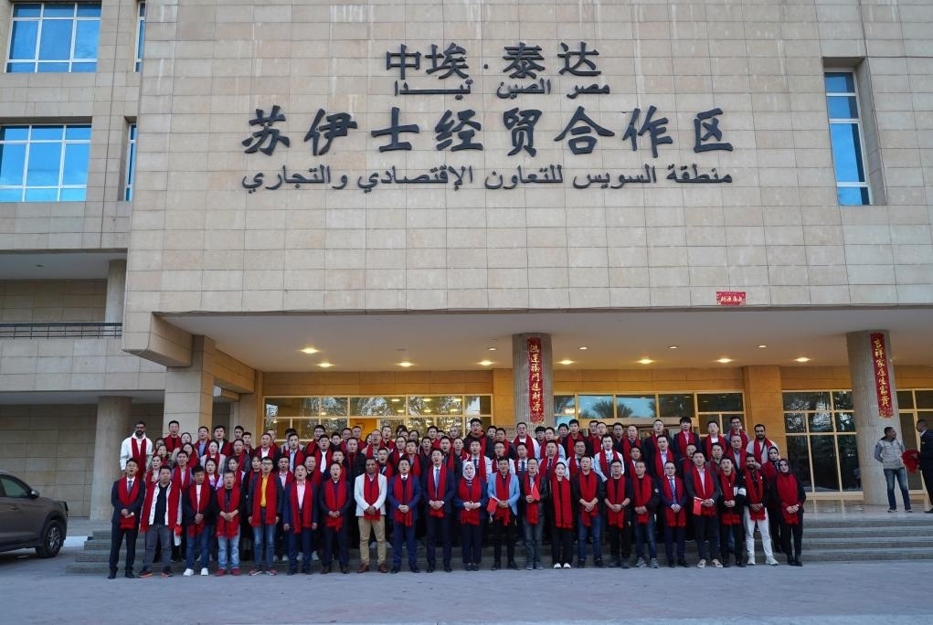 2024年2月11日，在位于埃及蘇伊士省的中埃·泰達蘇伊士經(jīng)貿(mào)合作區(qū)，中埃員工在合作區(qū)辦公大樓前合影拜年。新華社發(fā)（泰達合作區(qū)供圖）