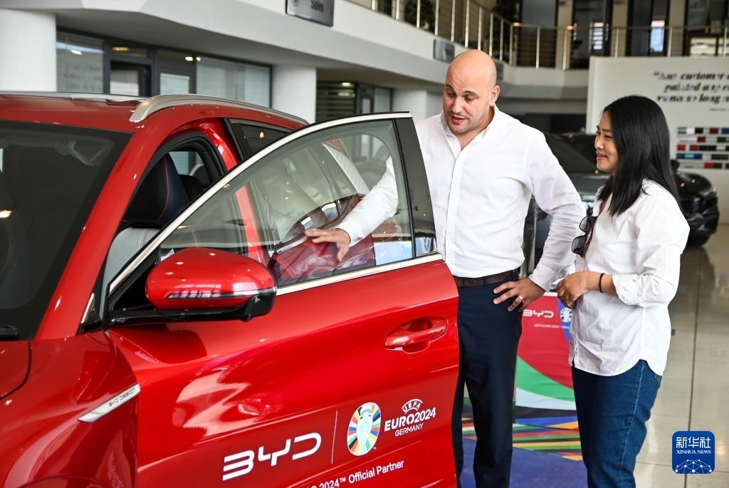 2024年5月29日，在馬耳他比爾基卡拉，馬耳他哈桑-扎米特汽車公司首席執(zhí)行官德古阿拉（左）介紹一輛比亞迪純電動汽車。新華社發(fā)（喬納森·博格 攝）