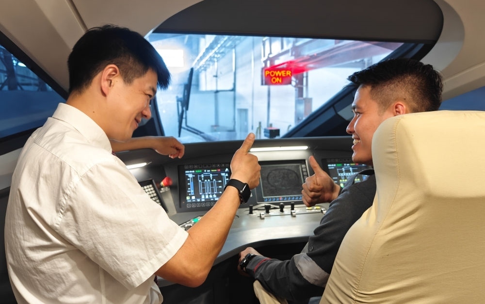 2023年8月25日，在印度尼西亞萬隆的雅萬高鐵德卡魯爾動車所內(nèi)，中國師傅穆振（左）向印尼火車司機塞蒂亞萬講解動車組出庫前的上電作業(yè)。新華社記者 徐欽 攝