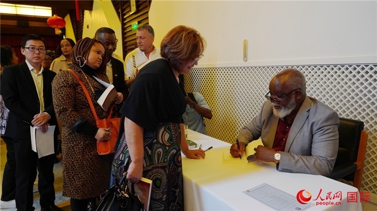 譚哲理在活動(dòng)現(xiàn)場(chǎng)簽名贈(zèng)書。人民網(wǎng) 劉暢攝