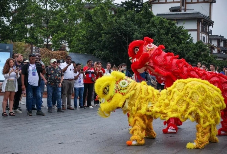 2024“一帶一路”媒體合作論壇聯(lián)合采訪調(diào)研行成員在樂(lè)山蘇稽古鎮(zhèn)觀看非遺舞獅表演。本報(bào)記者 伊霄攝