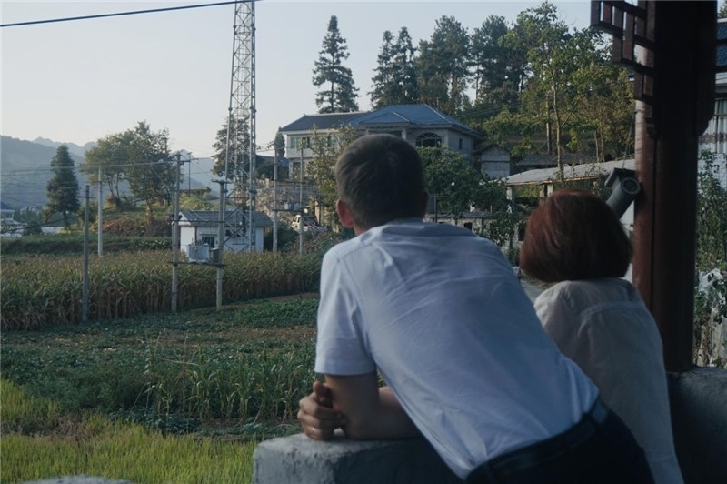 望得見山，看得見水，記得住鄉(xiāng)愁。每個(gè)人心中都有一個(gè)屬于自己的“花茂村”，在這方心田，走遍千山萬水，鄉(xiāng)音未改鬢毛衰。吉爾吉斯斯坦《比什凱克晚報(bào)》第一副總編輯妮娜·尼奇博洛娃與《中國與俄羅斯》雜志社社長奧列格·別列日內(nèi)赫攝在花茂村民居屋檐下并肩佇立，眺望山水，尋覓鄉(xiāng)愁。（李光裕攝）