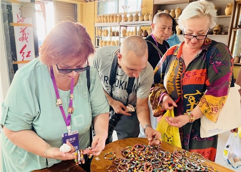 歐亞媒體考察團(tuán)成員在母氏陶藝館內(nèi)挑花了眼，色彩絢麗、質(zhì)地均勻的陶藝手串讓他們愛不釋手?！斑@里的東西都太實(shí)惠了！”塔吉克斯坦《索格特真理報(bào)》政論部主任娜塔利婭·多羅費(fèi)耶娃說。花茂村的特色產(chǎn)品物美價(jià)廉，讓考察團(tuán)成員為家人好友買到了心儀的禮物，也為此次以四川成都為起點(diǎn)，路經(jīng)南充、廣安至貴州遵義的考察行程畫上了圓滿句號(hào)。（張亞欣攝）