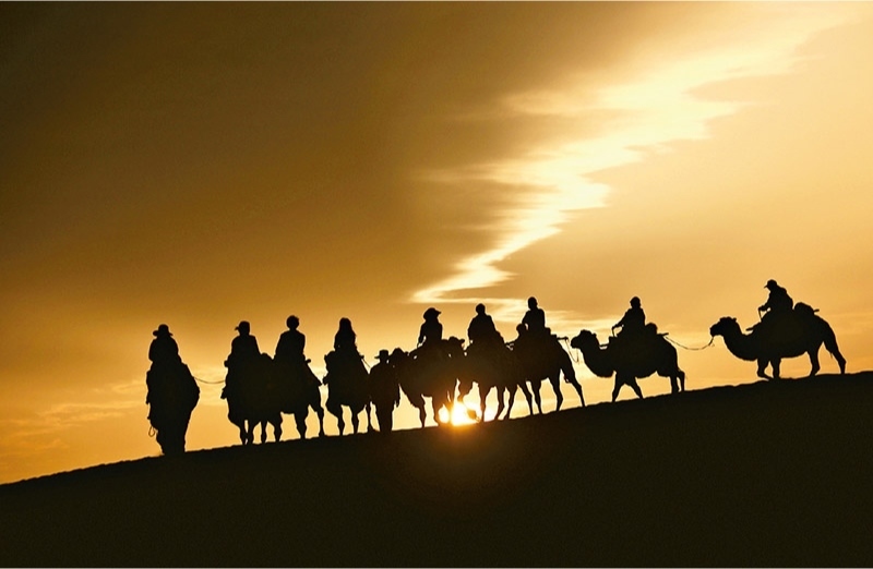 新時(shí)代以來，文化和旅游深度融合發(fā)展體制機(jī)制不斷健全，成功走出了一條獨(dú)具特色的中國(guó)旅游發(fā)展之路。圖為2024年9月1日清晨，游客在甘肅省敦煌市鳴沙山月牙泉景區(qū)乘騎駱駝，欣賞大漠風(fēng)光，體驗(yàn)絲路風(fēng)情。 新華社發(fā) 張曉亮/攝