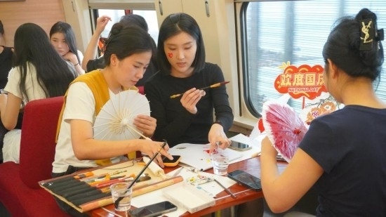 10月1日，旅客們在G1634次列車上給油紙傘作畫。新華社記者周義 攝