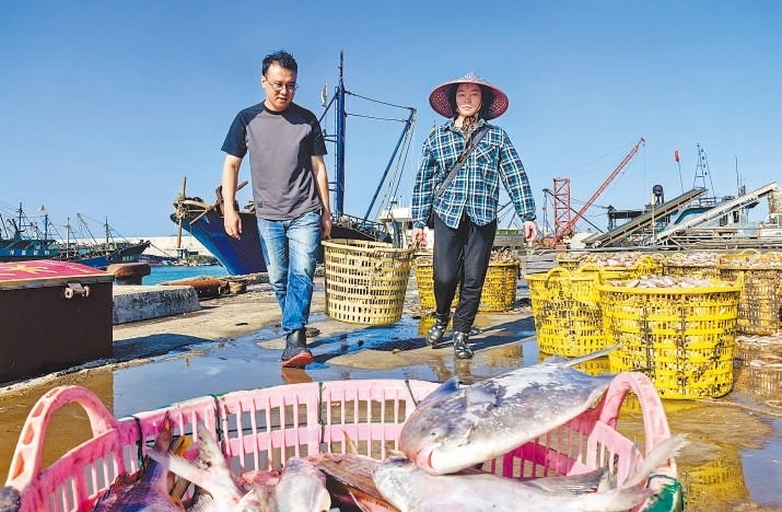 許小斌(左)和漁民一起搬運(yùn)海鮮。本報記者 付 文攝