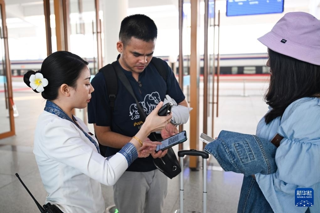 10月12日，在老撾萬象中老鐵路萬象站，工作人員檢驗(yàn)乘客車票。新華社記者 程一恒 攝