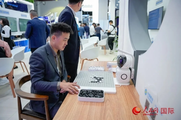 觀眾在中國移動(dòng)國際有限公司展臺體驗(yàn)智慧圍棋機(jī)器人。人民網(wǎng) 塔里克·易卜拉欣攝