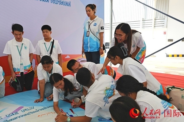 泰國學生在開營儀式展板上繪制圖案。人民網(wǎng)記者 白元琪攝