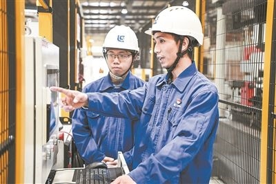 在廣西柳工機(jī)械股份有限公司生產(chǎn)車間內(nèi)，一名高級技師（右）給徒弟講解數(shù)控設(shè)備操作細(xì)節(jié)。新華社記者 曹祎銘攝