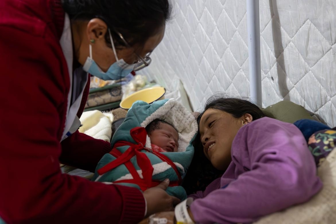 1月10日，定日縣中心醫(yī)院的婦產(chǎn)科醫(yī)生悉心照看一位母親和她懷里的新生兒。人民日?qǐng)?bào)記者張武軍攝