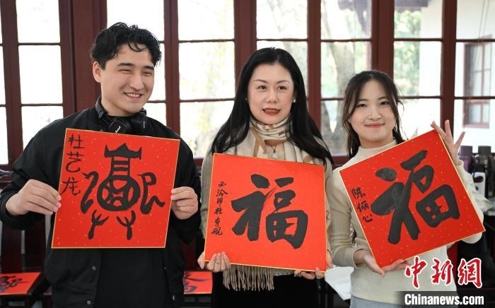 1月20日，外籍留學(xué)生和西泠印社社員李硯(中)展示各自創(chuàng)作的福貼。當(dāng)日，來(lái)自巴西、馬來(lái)西亞、加納、哈薩克斯坦的外籍留學(xué)生在浙江杭州西泠印社體驗(yàn)福貼、春聯(lián)和篆刻，感受古老的中國(guó)傳統(tǒng)文化。中新社記者 王剛 攝