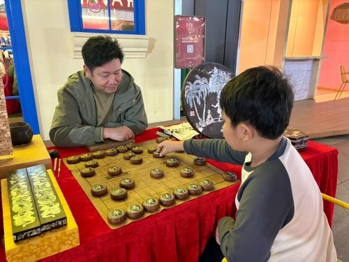 柯秋楓與市民下椰雕象棋。人民網(wǎng) 陳葉欣攝