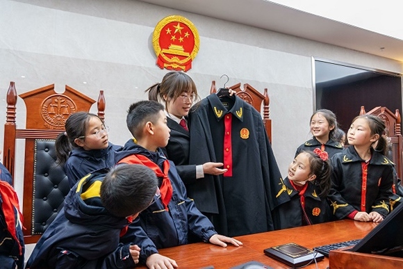 圖②：干警向同學(xué)們介紹法袍。