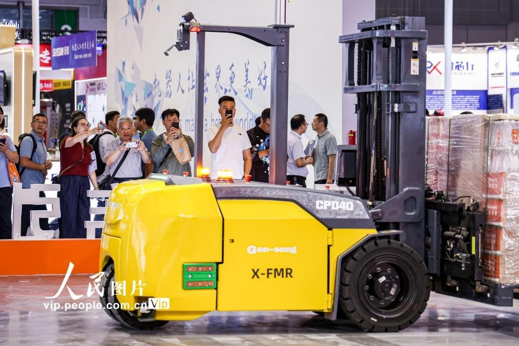第24屆中國工博會現(xiàn)場，觀眾觀看叉取機(jī)器人作業(yè)演示。王初攝（人民圖片網(wǎng)）