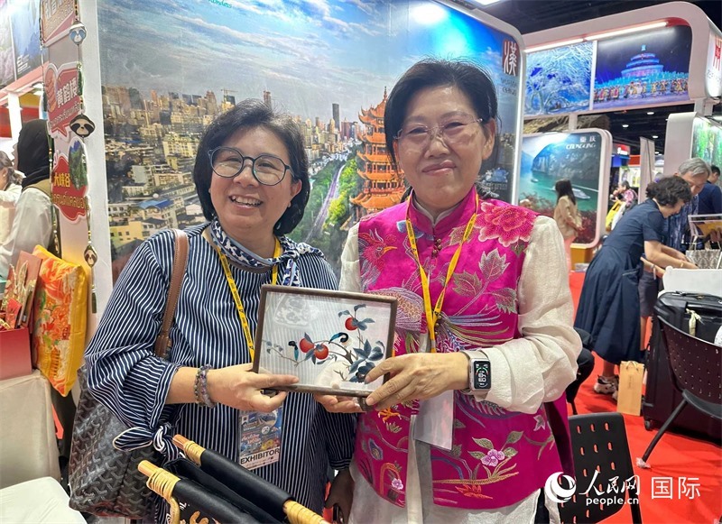 中國“大冶刺繡”傳承人劉小紅（右）參加泰國國際旅游展，向觀眾介紹中國非遺刺繡針法。人民網(wǎng)記者 簡承淵攝