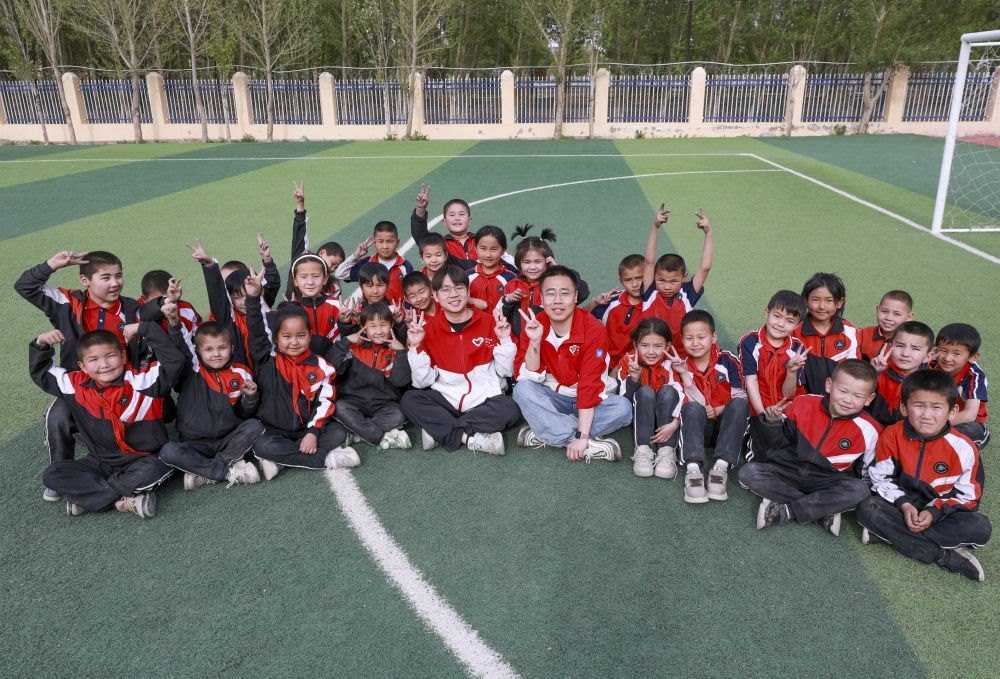 4月23日，在新疆克州阿圖什市哈拉峻鄉(xiāng)謝依特小學(xué)，支教教師王俊文（中左）、李軻凡（中右）和學(xué)生在一起。